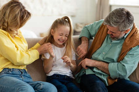 Cheerful Family Playing Having Fun, Parents Tickling Daughter Indoorの写真素材