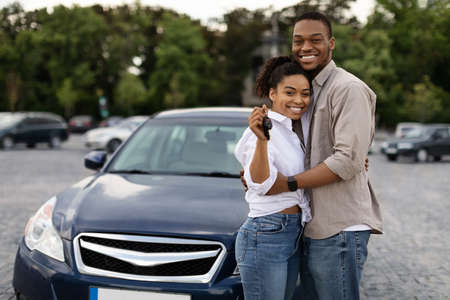 Happy African Couple Showing New Car Key Hugging Standing Outdoorsの写真素材