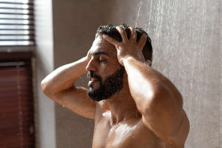 Handsome young Arabic male model taking hot showerの写真素材