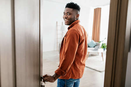 Joyful African American Male Entering His New Apartment Opening Doorの写真素材