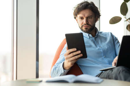 Portrait of focused man using digital tablet and pc