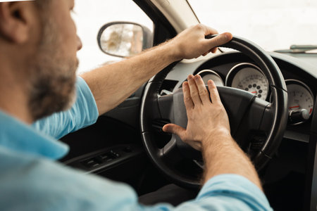 Adult man driving car and honking, pressing horn
