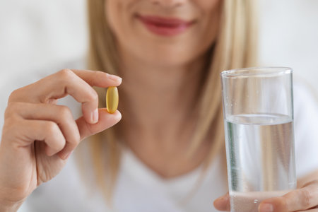 Cropped of blonde lady holding pill and glass of waterの写真素材