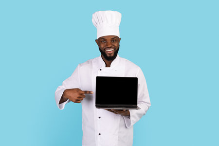 Cooking Website. Smiling Black Chef Pointing At Blank Laptop In His Handの写真素材