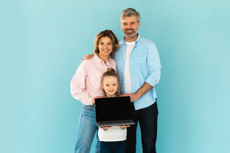 Family Of Three Showing Laptop Empty Screen On Blue Backgroundの写真素材