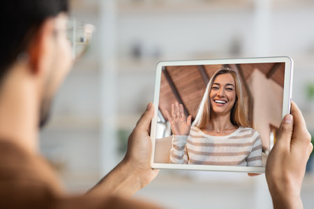 Unrecognizable young man holding digital tablet, having video conferenceの写真素材
