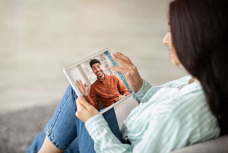 Unrecognizable lady using tablet pc, calling her boyfriend