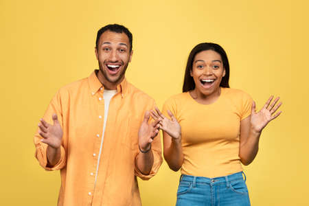 Excited young black couple screaming WOW, cannot believe win or success, overjoyed about big sale on yellow backgroundの写真素材