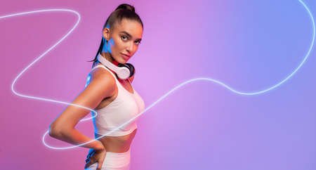 Fit Woman With Wireless Headphones Standing On Neon Background