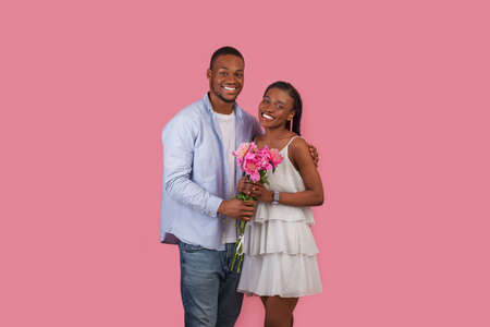 Happy black man making surprise for woman giving flowers