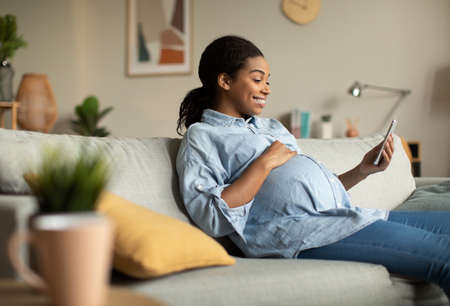 Cheerful Pregnant African Lady Using Smartphone Video Calling At Home