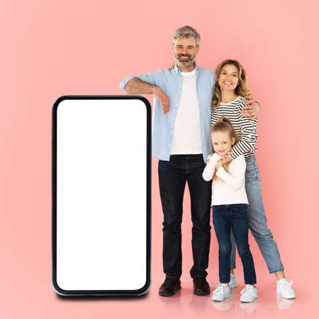 Family Posing With Huge Smartphone With Empty Screen In Studioの写真素材