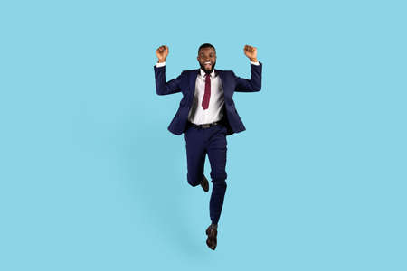 Business Win. Joyful Black Businessman In Suit Jumping With Clenched Fistsの写真素材