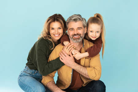 Cheerful Family Hugging Smiling To Camera Posing Over Blue Background