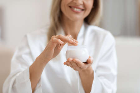 Cropped of blonde woman holding jar with creamの写真素材