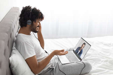 Happy eastern man having online party with friend, using laptop