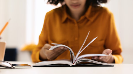 Education and free time. Young black woman reading book or writing notes in notepad, sitting at desk...