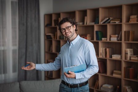 Happy european handsome millennial male psychologist in glasses invites client in clinic office interiorの写真素材