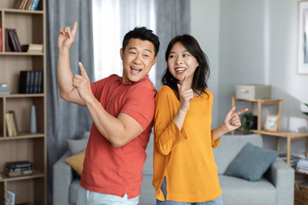 Funny asian man and woman having good time at homeの写真素材