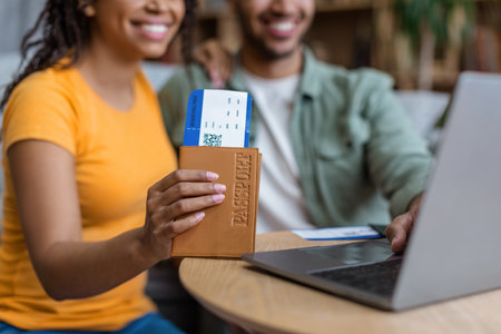 Online tickets booking and summer vacation concept. Black spouses buying hot tour, woman holding passport with ticketsの写真素材