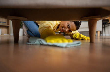 Unhappy African Lady Mopping And Dusting Floor With Rag Indoorの写真素材