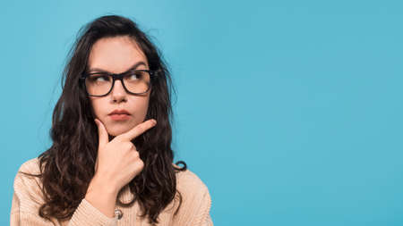 Pensive smart millennial caucasian female student in glasses show finger at empty space, think,...