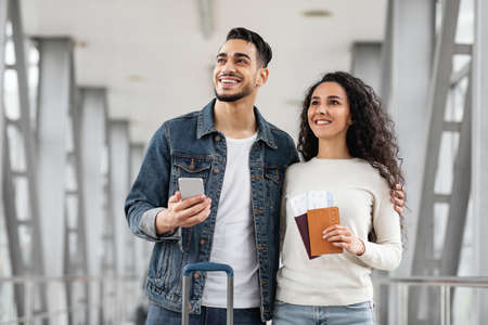 Millennial Arab Couple Standing At Airport Together And Looking Away