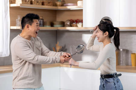 Funny japanese couple having good time while cooking togetherの写真素材