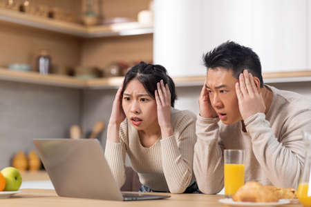 Shocked asian couple looking at laptop screenの写真素材