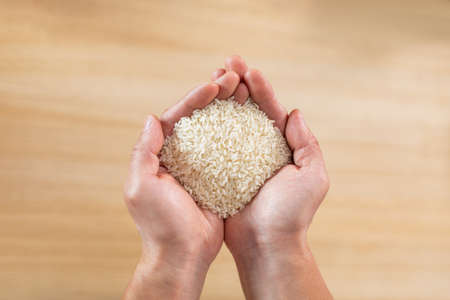 Top view of unrecognizable person hands with handful of riceの写真素材