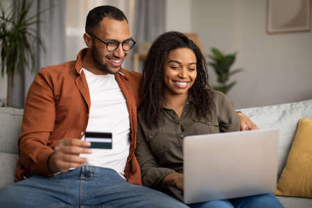 African Couple Shopping Online Via Laptop And Credit Card Indoorの写真素材
