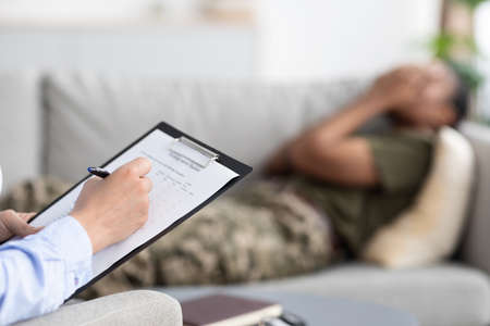 Psychological Therapy. Female Psychiatrist Filling Questionnaire During Meeting With Black Female Soldierの写真素材
