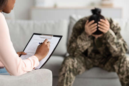Black Psychiatrist Lady Filling Questionnaire During Therapy Meeting With Depressed Military Womanの写真素材