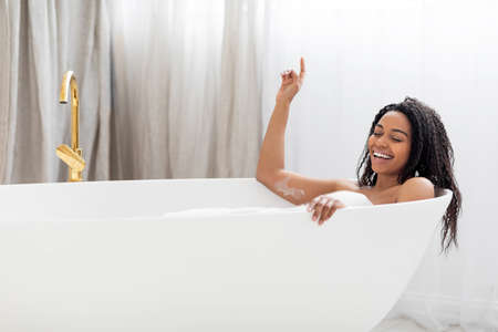 Carefree Black Lady Singing And Having Fun While Relaxing In Bathtub