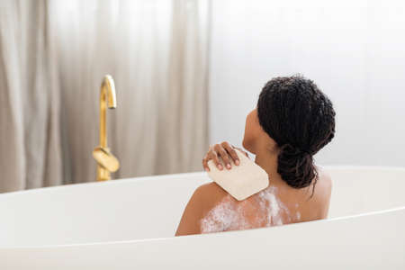 Young Black Lady Washing Herself With Sponge While Taking Bath At Home