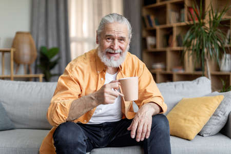 Senior man drinking coffee and smiling, home interior