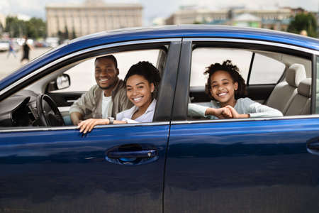 Happy Black Family Sitting In New Blue Car In Cityの写真素材