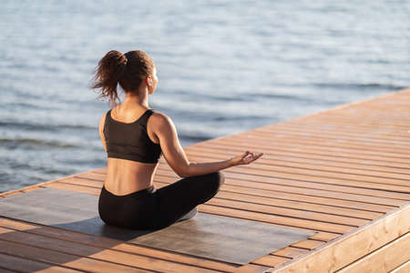 Unrecognizable african american woman meditating by waterの写真素材