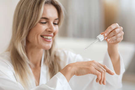 Positive blonde lady testing brand new beauty productの写真素材