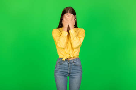 Unrecognizable Lady Covering Face Posing Standing Over Green Studio Backgroundの写真素材