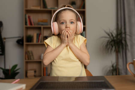 Shocked Kid Girl Looking At Laptop Making Video Call Indoor