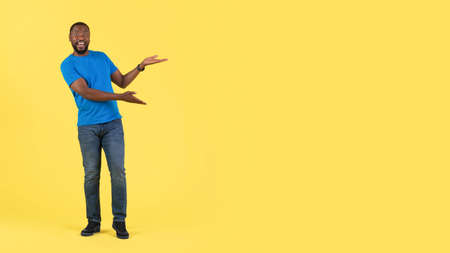 Excited Black Guy Gesturing Pointing At Free Space, Yellow Background