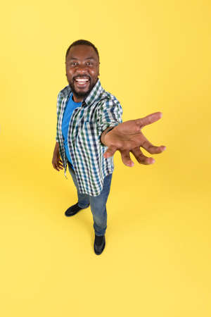 African Male Stretching Hand Holding Invisible Object, Yellow Background, Verticalの写真素材