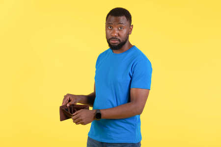 Unhappy Black Man Showing Empty Wallet Having Financial Problems, Studio