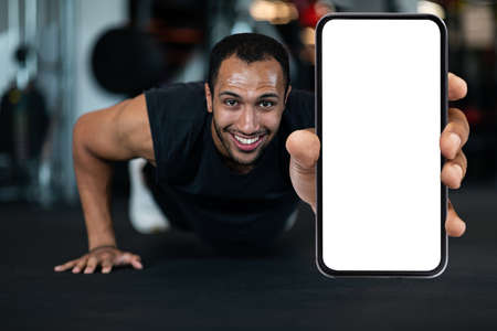 Fitness Offer. Sporty Black Man Showing Blank Smartphone While Doing Push-Upsの写真素材