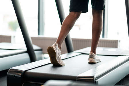 Rear View Of Unrecognizable Black Male Legs Jogging On Treadmill In Gymの写真素材