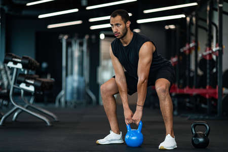 Motivated Young Black Man Training With Kettlebell At Modern Gym Interiorの写真素材