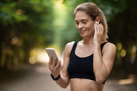 Pretty athletic woman answering phone call while training outdoors