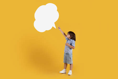 Adorable little boy pointing at empty speech bubble, feeling excited of news, full length, free...