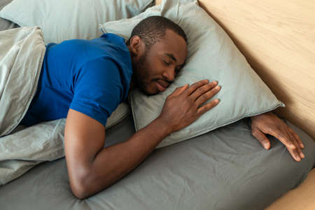 Sleeping African American Man Lying Resting In Bedroom, Above View